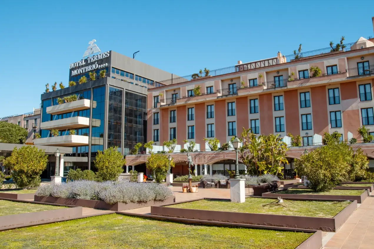 Fachada del Hotel Termes Montbrió bajo un cielo azul, con sus jardines