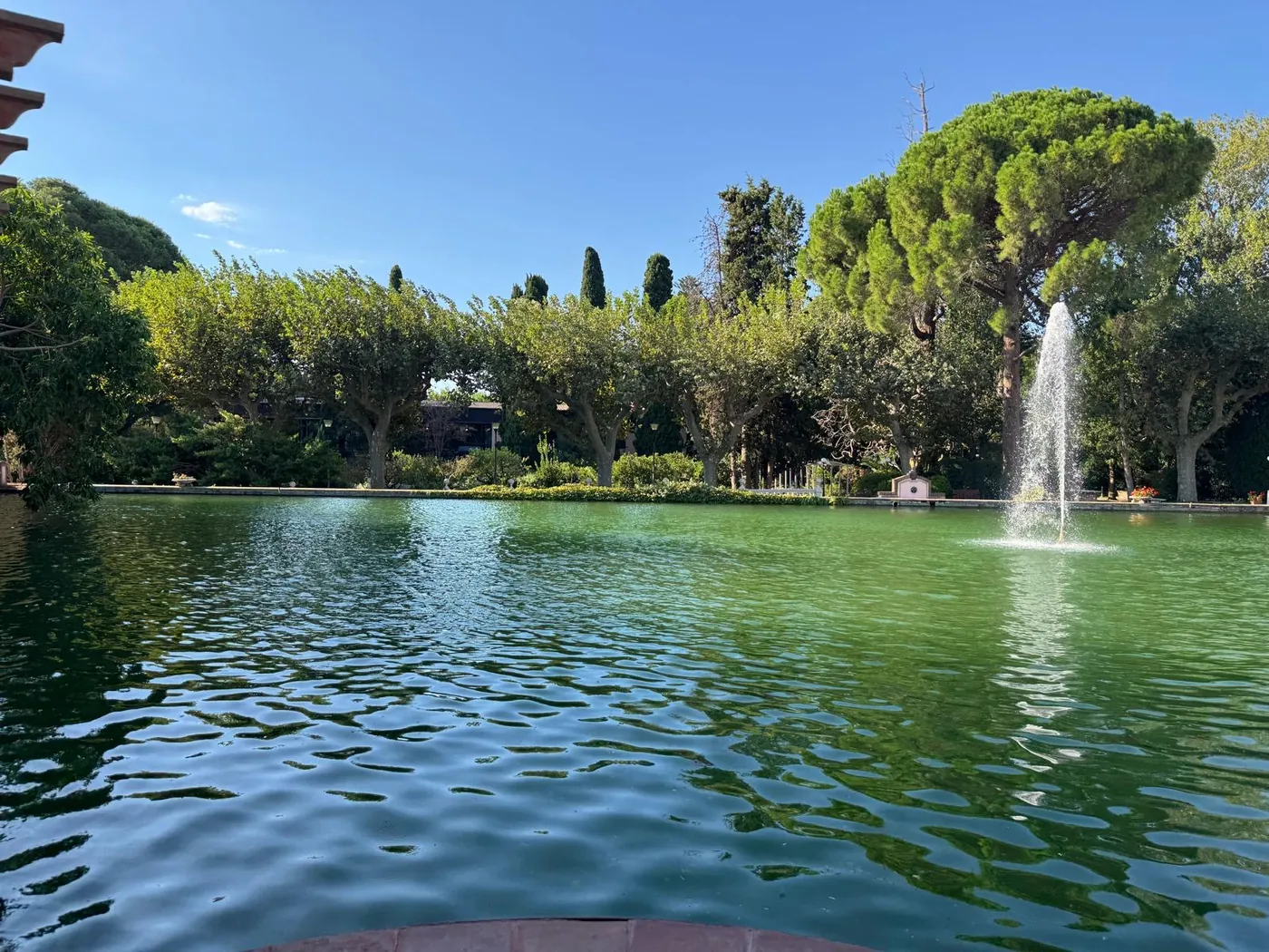 Lago con una fuente rodeado de árboles en los jardines del hotel